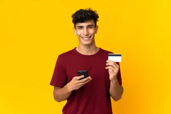 Jonge Argentijnse Man Geïsoleerd Gele Achtergrond Kopen Met Mobiele Telefoon — Stockfoto