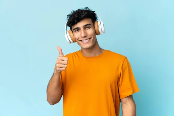 Joven Argentino Aislado Sobre Fondo Escuchando Música Con Pulgar Hacia — Foto de Stock
