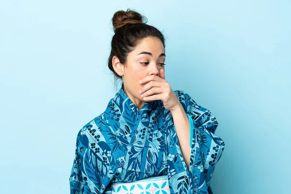 Kimono giyen bir kadın, yalıtılmış arka planda sürpriz jest yapıyor.