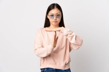 Genç Çinli bir kız izole edilmiş beyaz bir arka planda jest yapıyor.