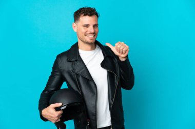 Motosiklet kasklı beyaz adam mavi arka planda izole edilmiş gururlu ve kendini beğenmiş.