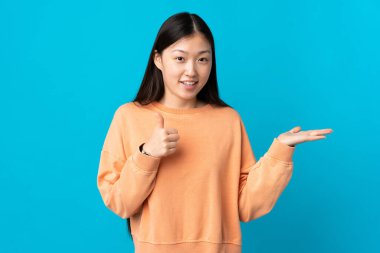 Mavi arka plan üzerinde genç Çinli bir kız. Avucunun içinde hayali bir şey tutuyor. Bir ilan vermek için.