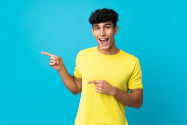 Arka planda izole edilmiş genç Arjantinli adam şaşırmış ve işaret ediyor.