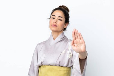 Kimono giyen bir kadın, izole edilmiş arka planda durup jest yapıyor.