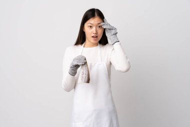 Çinli balıkçı önlük takıyor ve beyaz arka planda çiğ balık tutuyor. Bir şey fark etti ve çözümü arıyor.