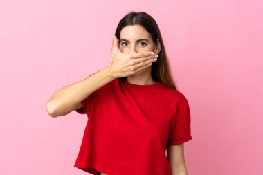 Pembe arka planda izole edilmiş, ağzı elle kaplanmış beyaz bir kadın.