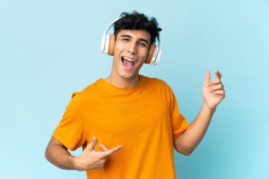 Arjantinli genç adam arka planda izole edilmiş müzik dinliyor ve gitar hareketi yapıyor.