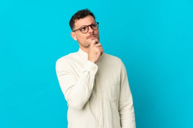 Beyaz tenli yakışıklı bir adam mavi arka planda izole edilmiş ve yukarı bakıyor.