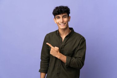 Arka planda izole edilmiş genç Arjantinli bir adam bir ürün sunmak için kenarı işaret ediyor