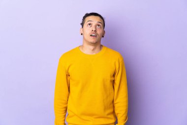 İzole edilmiş arka planda beyaz bir adam yukarı bakıyor ve şaşırmış bir ifadeyle