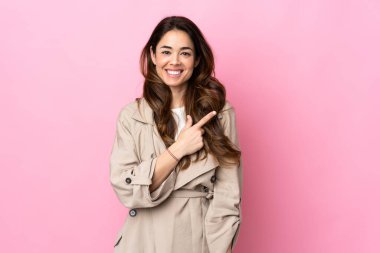 İzole edilmiş arka planda bir kadın bir ürün sunmak için kenarı işaret ediyor