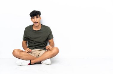 Genç Arjantinli adam yerde oturuyor ve yüzünde sürpriz bir ifade var.