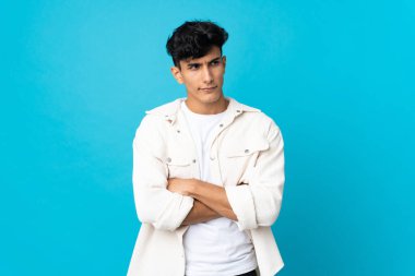 Arjantinli genç adam arka planda izole olarak kollarını kavuşturuyor.