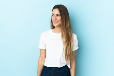 Kafkasyalı genç bir kadın soyutlanmış arka planda, yana bakıyor ve gülümsüyor.