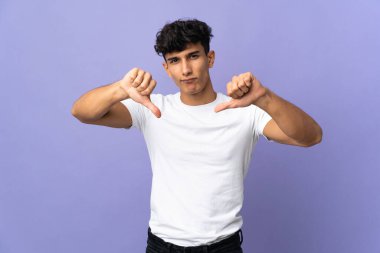 Arjantinli genç adam arka planda iki eliyle baş parmağını gösteriyor.