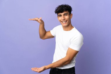 Arjantinli genç bir adam arka planda izole edilmiş bir ilan vermek için kopyalama alanı tutuyor.