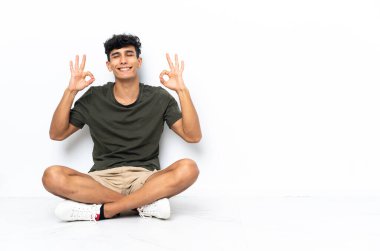 Zen pozuyla yerde oturan genç Arjantinli adam.