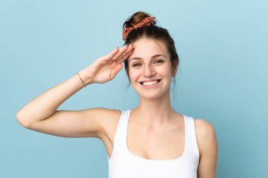 Mavi arka planda izole edilmiş beyaz bir kadın. Mutlu bir ifadeyle selamlıyor.