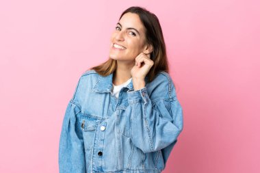 Pembe arka planda izole edilmiş genç beyaz kadın gülüyor.