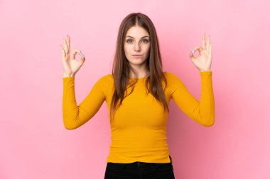 Zen pozunda pembe arka planda izole edilmiş beyaz bir kadın.