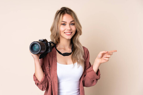 Young photographer girl over isolated background pointing finger to the side