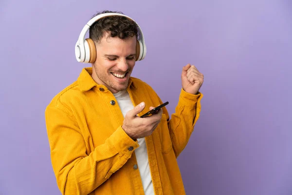 Joven Hombre Guapo Caucásico Aislado Sobre Fondo Púrpura Escuchando Música — Foto de Stock