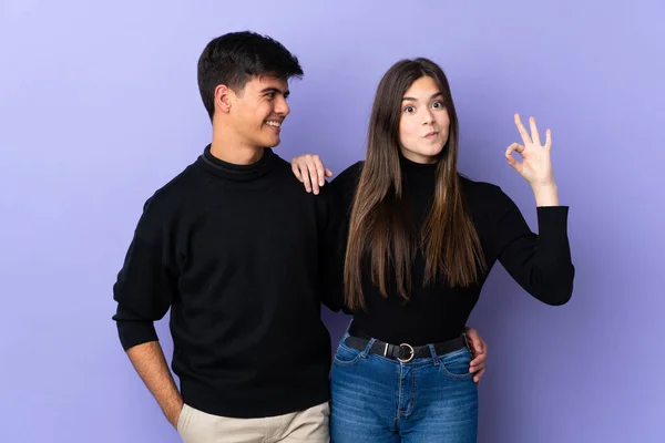 Casal Jovem Sobre Fundo Roxo Isolado Mostrando Sinal Com Dedos — Fotografia de Stock