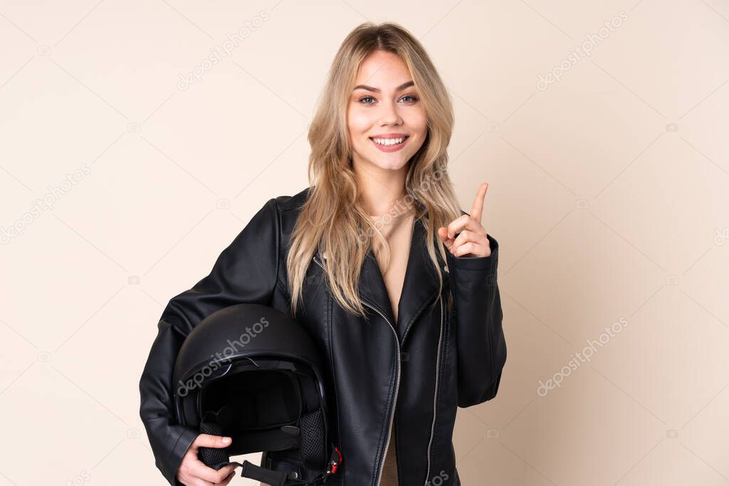 Russian girl with a motorcycle helmet isolated on beige background pointing up a great idea