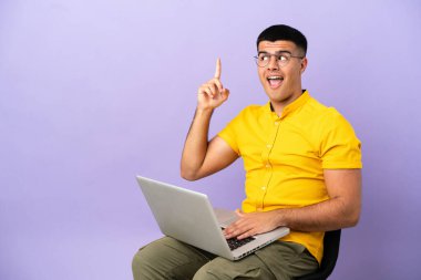 Dizüstü bilgisayarlı bir sandalyede oturan genç adam parmağını kaldırarak çözümü anlamaya çalışıyor.