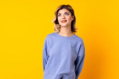 Genç Rus kadın sarı arka planda izole edilmiş ve yukarı bakıyor.