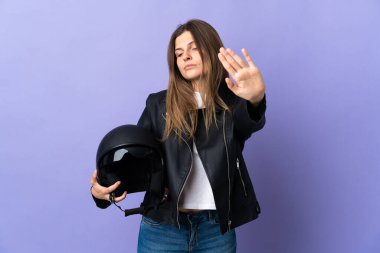 Mor arka planda motosiklet kaskı tutan genç Slovak kadın dur hareketi yapıyor ve hayal kırıklığına uğruyor.