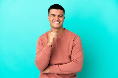 Genç, yakışıklı, soyutlanmış, mavi arka plan gülüyor.