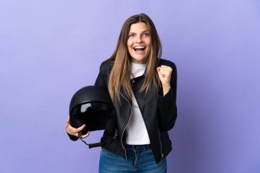Mor arka planda motosiklet kaskı tutan genç Slovak kadın galibiyeti kutluyor.