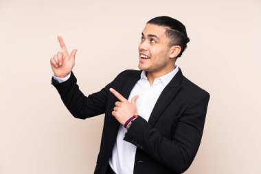 Asyalı iş adamı bej arka planda izole edilmiş işaret parmağıyla işaret etmek harika bir fikir.