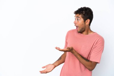 Genç, yakışıklı Brezilyalı bir adam beyaz arka planda izole edilmiş sürpriz bir ifadeyle yan tarafa bakarken