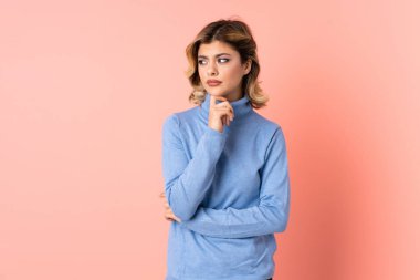 Pembe arka planda izole edilmiş genç bir Rus kadının şüpheleri ve düşünceleri var.