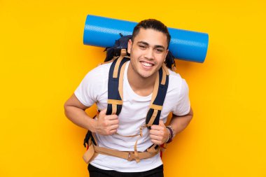 Tecrit edilmiş arka planda büyük bir sırt çantası olan genç dağcı.