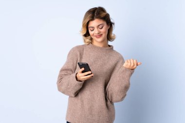 Mavi arka planda izole edilmiş genç bir Rus kadın şaşırdı ve bir mesaj gönderiyor.