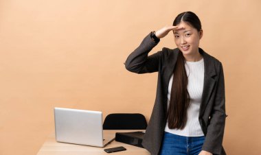 İş yerindeki Çinli iş kadını bir şeye bakmak için çok uzaklara bakıyor.