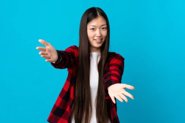 Genç Çinli kız mavi arka planda. Sunar ve davet eder.