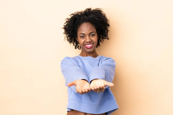 Jonge Afro Amerikaanse Vrouw Geïsoleerd Beige Achtergrond Houden Copyspace Imaginair — Stockfoto