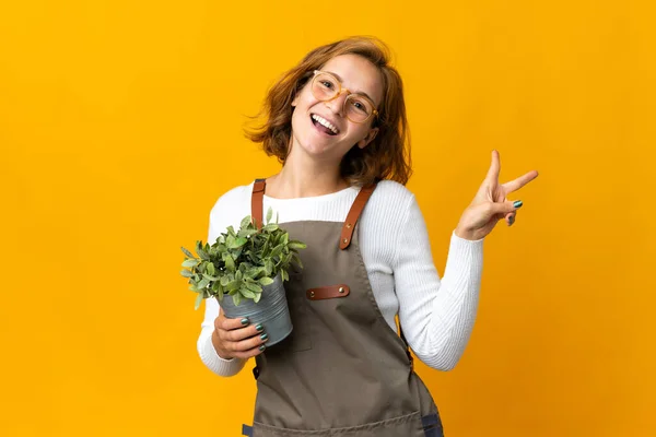 Giovane Donna Georgiana Possesso Una Pianta Isolata Sfondo Giallo Sorridente — Foto Stock