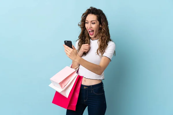 Ung Kaukasisk Kvinna Isolerad Blå Bakgrund Håller Shoppingväskor Och Skriva — Stockfoto