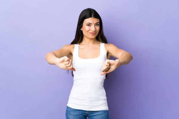 年轻的黑发女人 用双手在孤立的紫色背景上伸出大拇指 — 图库照片