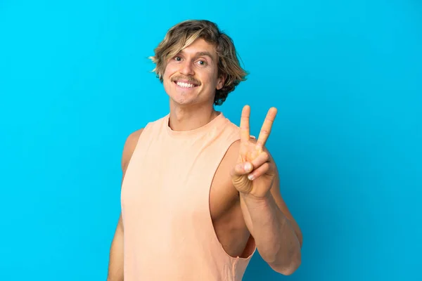 Bonito Loira Homem Isolado Fundo Azul Sorrindo Mostrando Sinal Vitória — Fotografia de Stock