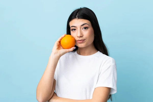 Ung Brunett Flicka Över Isolerad Blå Bakgrund Håller Orange — Stockfoto