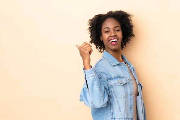 Młoda Afroamerykanka Odizolowana Beżowym Tle Wskazując Bok Aby Przedstawić Produkt — Zdjęcie stockowe