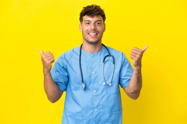 Jovem Cirurgião Homem Médico Isolado Fundo Amarelo Com Polegares Para — Fotografia de Stock