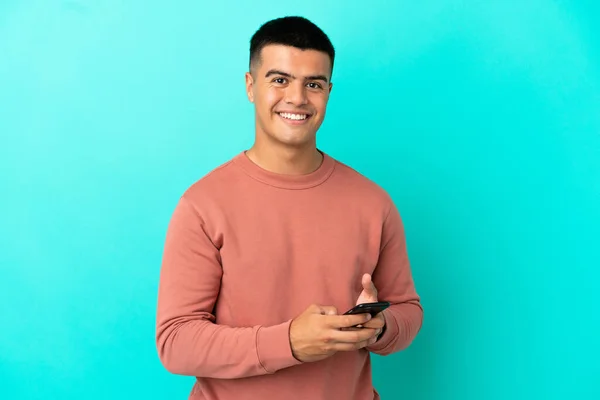 Joven Hombre Guapo Sobre Fondo Azul Aislado Enviando Mensaje Con — Foto de Stock