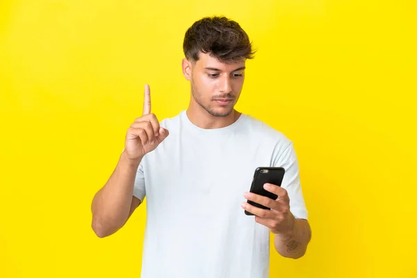 Mladý Kavkazský Pohledný Muž Izolované Žlutém Pozadí Pomocí Mobilního Telefonu — Stock fotografie